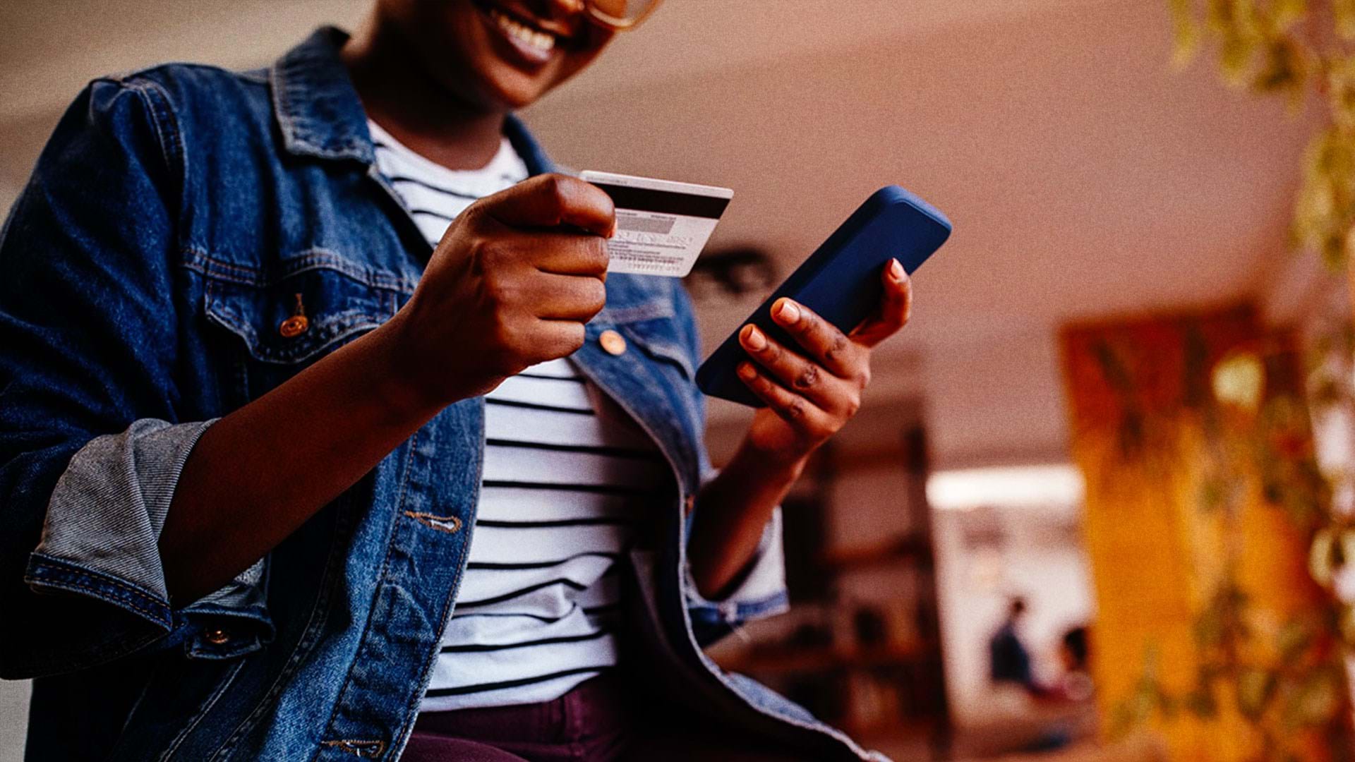 Woman shopping online with credit card and phone in hands