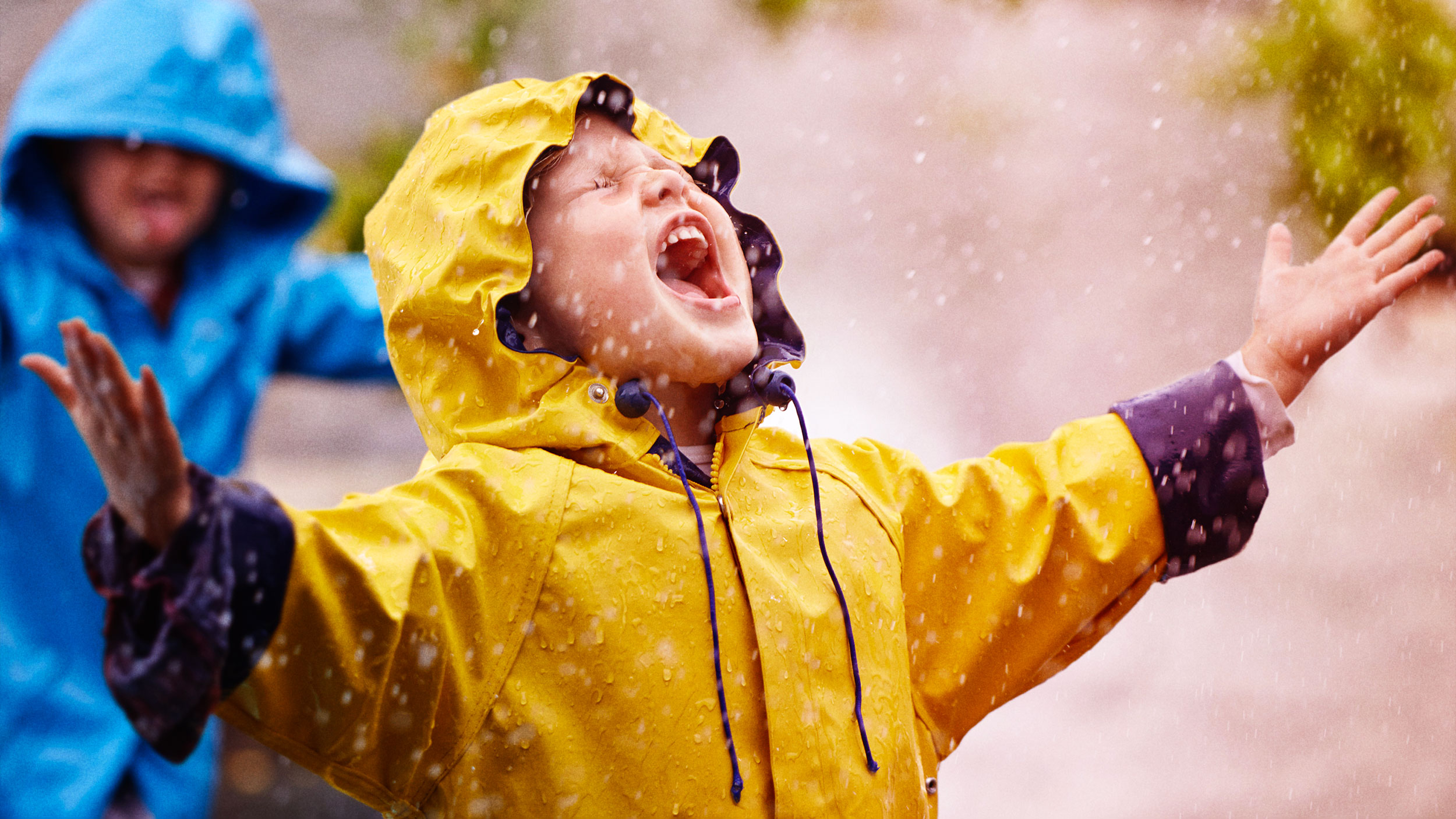 Happy child in the rain with yellow rain coat