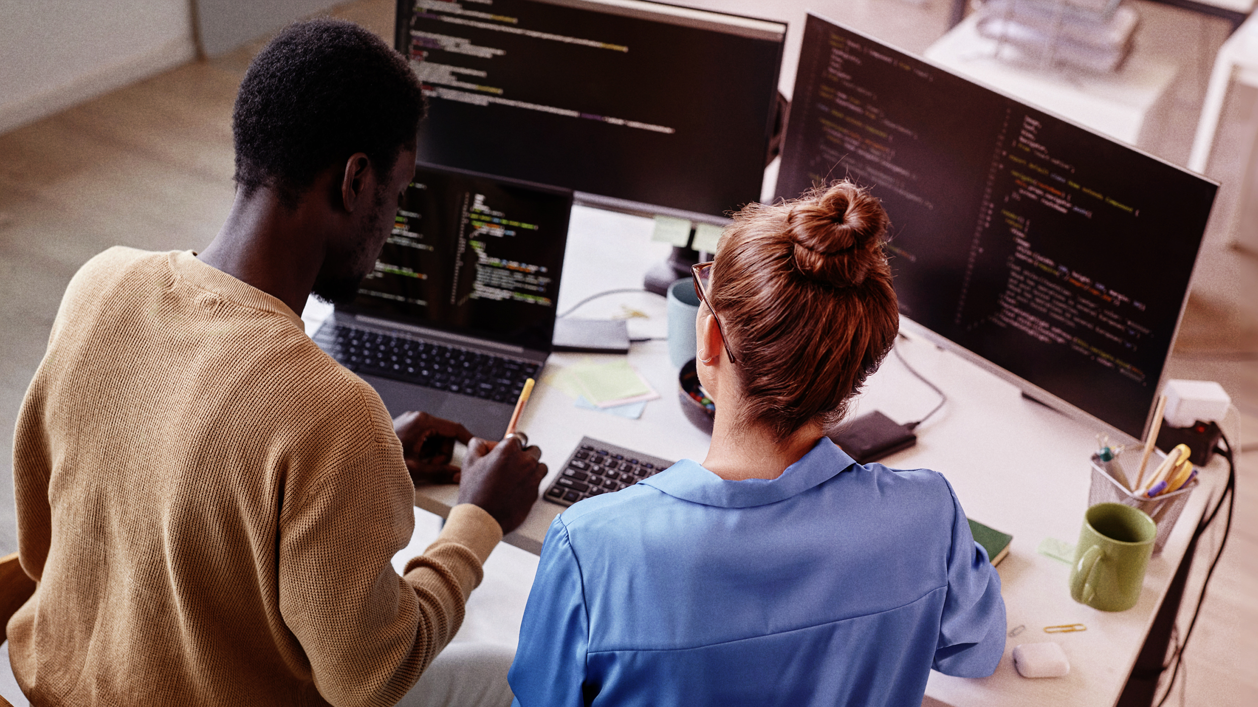 Two people working at computers at a desk 