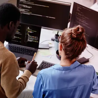 Two people working at computers at a desk 
