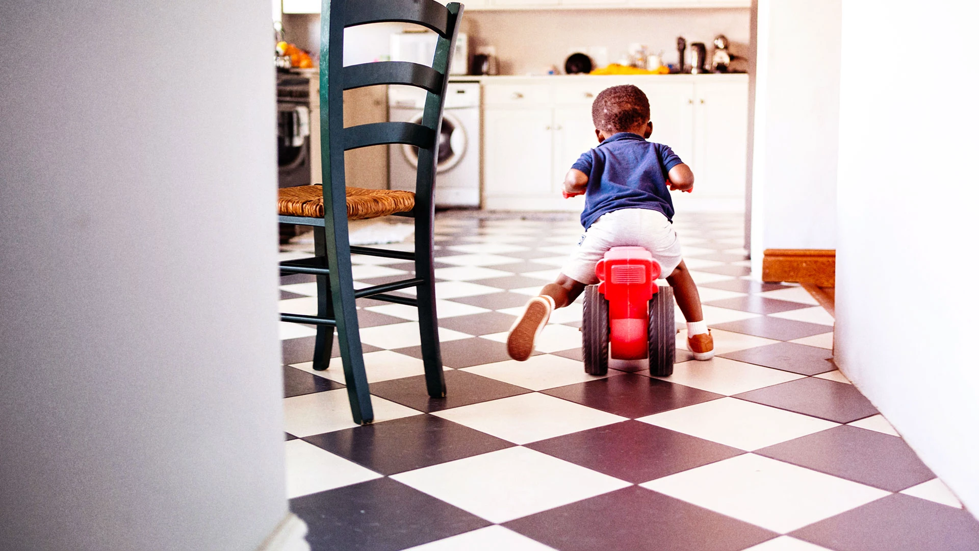 Boy child riding a bike in a kitchen  