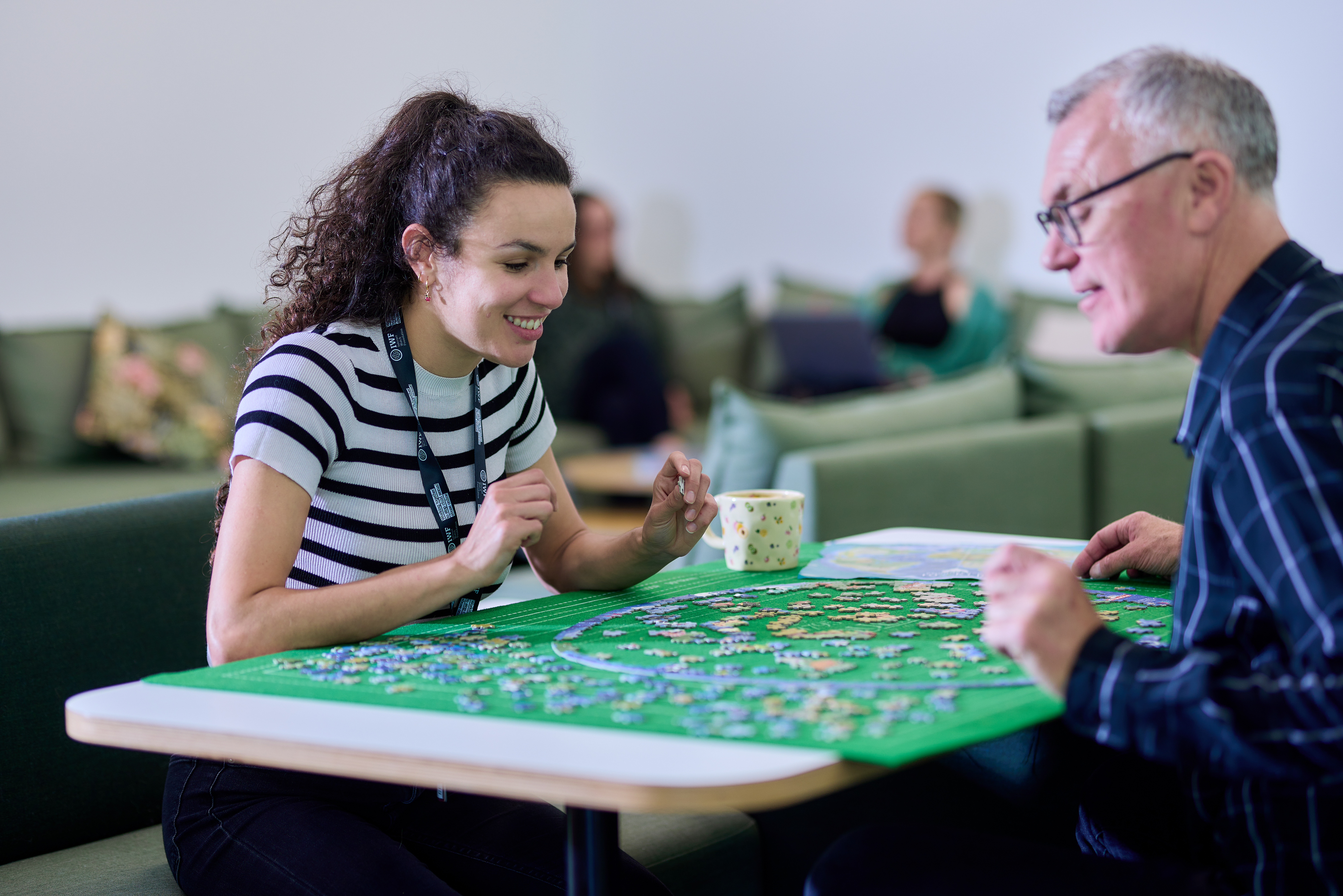 Two IWF colleagues doing a jigsaw puzzle together in a relaxed breakout area.