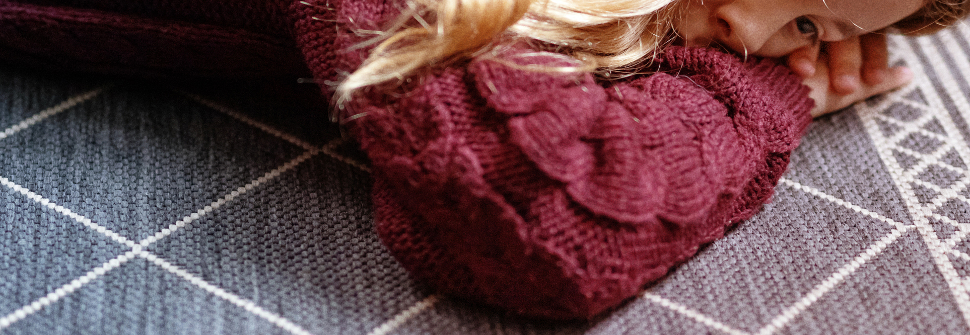 Sad girl sitting against a wall looking at her phone