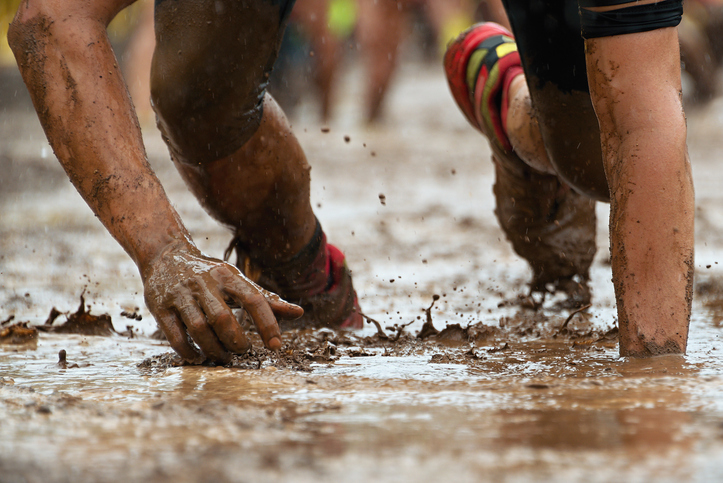 Man crawling through mud on an obstacle course. 