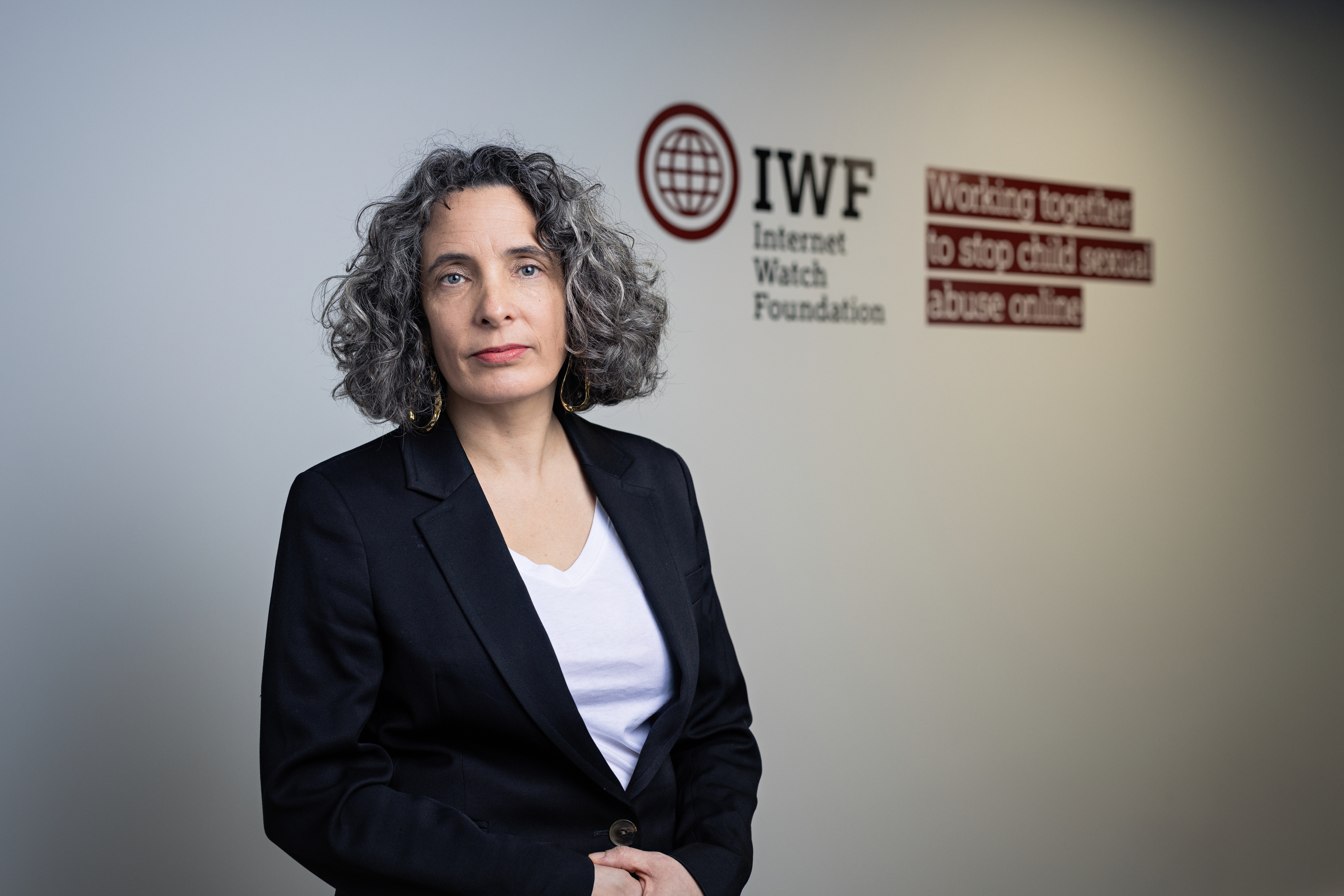 Kerry Smith, IWF CEO, standing next to IWF logo vinyl on wall